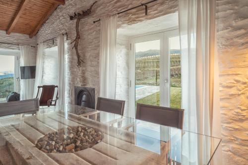 a dining room with a glass table and a fireplace at Quinta do Monte Travesso - Country Houses & Winery in Tabuaço
