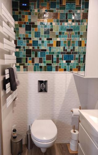 a bathroom with a toilet and a mosaic wall at City Art Inn in Szeged
