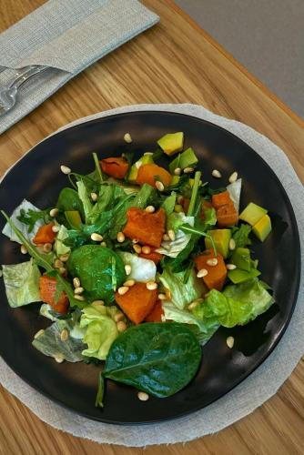 a black plate with a salad on a table at Ayhan Hotel in Aktobe