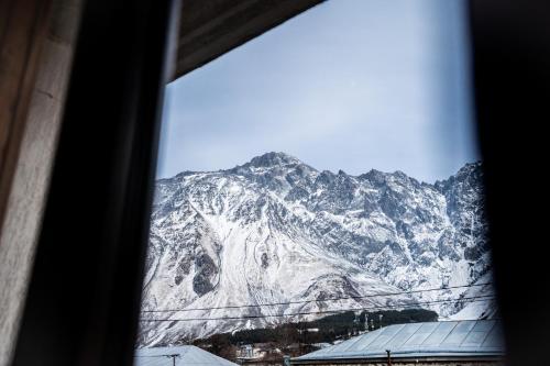 a view of a snow covered mountain from a window at Eltisy Guest House in Stepantsminda