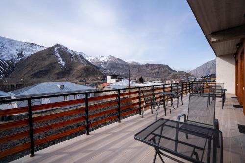 a balcony with tables and chairs and mountains at Eltisy Guest House in Stepantsminda