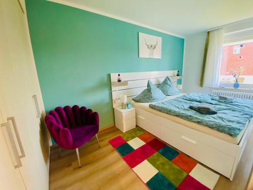 a bedroom with a bed and a purple chair at Strandnixe Cuxhaven in Cuxhaven