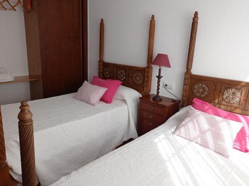 2 Betten in einem Schlafzimmer mit rosa und weiß in der Unterkunft Alojamiento rural Zona Bienestar in Aldeaquemada