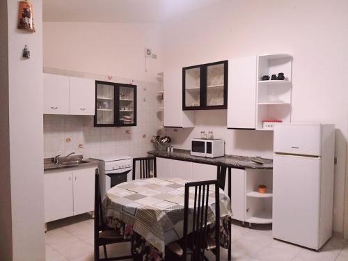 uma cozinha com armários brancos e uma mesa e cadeiras em By Azzurra Tra Mare e Montagna em Sìnnai