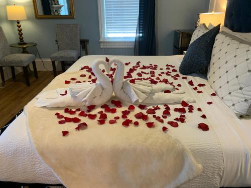 two white swans sitting on a bed covered in roses at Peace & Plenty Inn Bed and Breakfast Downtown St Augustine-Adults Only in Saint Augustine