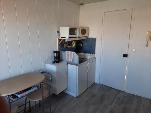 a small kitchen with a table and a microwave at Le pigeonnier 1 in Le Tréport