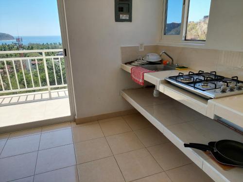 a kitchen with a stove and a sink and a window at Sunset House Zihuatanejo in Zihuatanejo