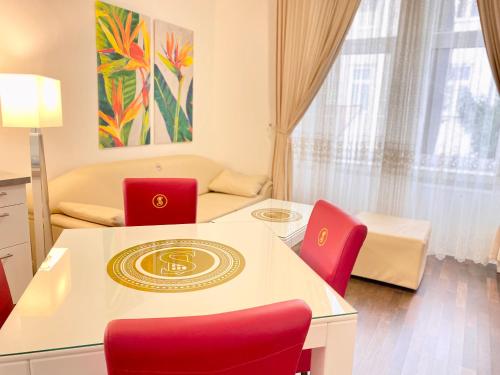a living room with a table and red chairs at Steiner Residences Vienna Augarten in Vienna