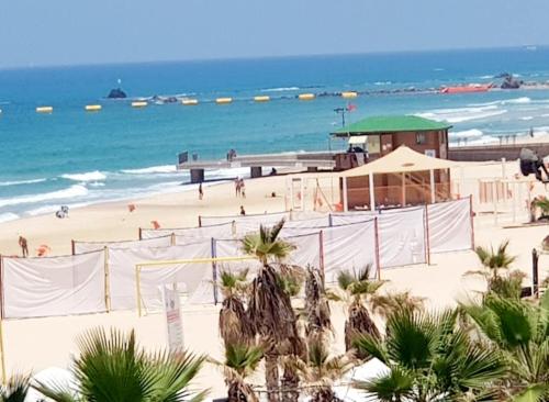 a beach with palm trees and the ocean at Hotel Apartment Short Term Tel Aviv Bat Yam 5 in Bat Yam