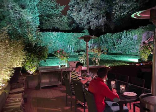 two men sitting at a table in a garden at night at Le jacuzzi de Marie ll in Tourcoing