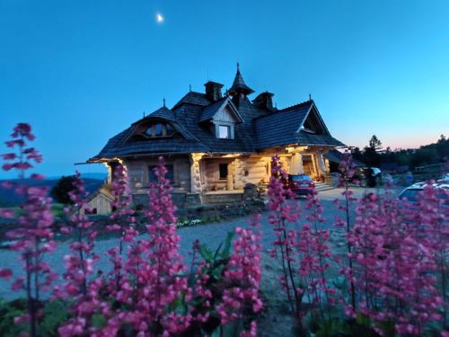 a house with a field of pink flowers in front of it at Wrzosowy Dwór - SPA in Skomielna Czarna