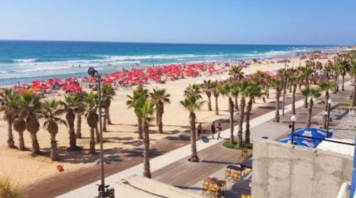 a beach with palm trees and umbrellas and the ocean at Hotel Apartment Short Term Tel Aviv Bat Yam 5 in Bat Yam