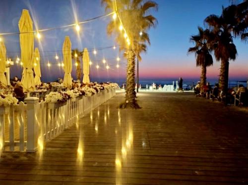 a row of tables and chairs with lights and palm trees at Hotel Apartment Short Term Tel Aviv Bat Yam 5 in Bat Yam