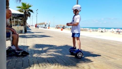 a young boy riding a skateboard on the beach at Hotel Apartment Short Term Tel Aviv Bat Yam 5 in Bat Yam