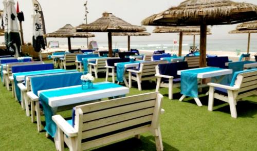 a row of tables and chairs with umbrellas on the beach at Hotel Apartment Short Term Tel Aviv Bat Yam 5 in Bat Yam