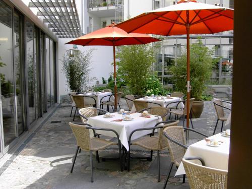 a group of tables with red umbrellas on a patio at Hotel Flandrischer Hof in Cologne