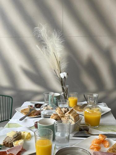 a table topped with breakfast foods and orange juice at Hôtel Les Sables - Urban Style - by Logis Hotels in Canet-en-Roussillon