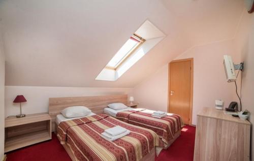 a attic bedroom with two beds and a skylight at Idilė Bed & Breakfast - Visaginas in Visaginas