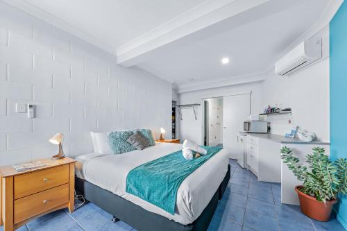 a bedroom with a large bed and a kitchen at Airlie Sun & Sand Accommodation Studio #1 in Airlie Beach