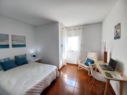 a bedroom with a bed and a desk with a laptop at Carcavelos Surf Beach House in Carcavelos