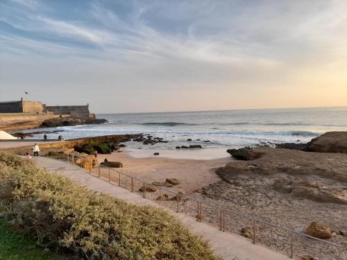 a beach with people walking on the sand and the ocean at Carcavelos Surf Beach House in Carcavelos