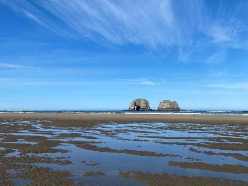 a beach with two large rocks in the ocean at Rockaway beach vibes,Waterfront Oceanfront Rockaway Beach House near Downtown,WIFI, Washer Dryer in Rockaway Beach