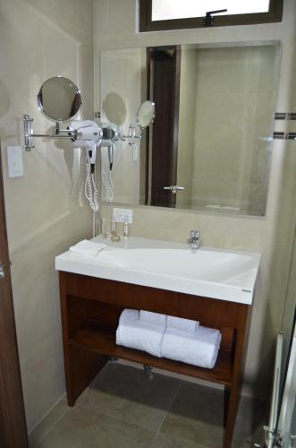 a bathroom with a sink and a mirror and towels at Hotel San Agustin Plaza in Latacunga