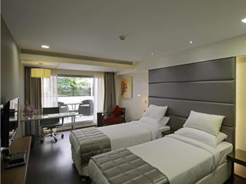 a hotel room with two beds and a desk at Hotel Grande 51 in Navi Mumbai