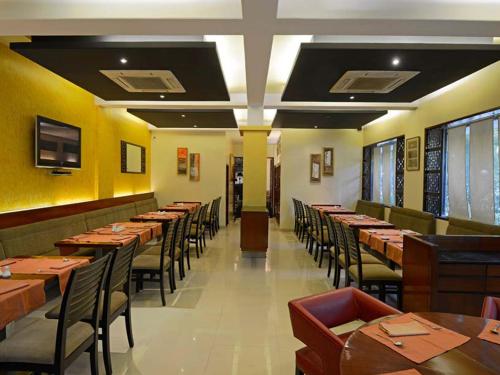 a restaurant with wooden tables and chairs and yellow walls at Hotel Grande 51 in Navi Mumbai