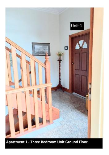 an entryway with a wooden staircase and a brown unitioned door at Ocean Aspect and Central to CBD - CoSheirm Apartments On Merri in Warrnambool