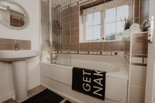 a bathroom with a tub and a sink and a mirror at Coyle House, 3 bed, super kings or twins, driveway, free wi-fi, pets, corporates welcome in Corby