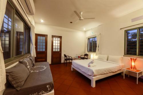 a living room with a bed and a couch at The Canopy Guest House in Auroville
