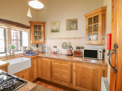 eine Küche mit Holzschränken und einem Waschbecken in der Unterkunft Bluebell Cottage in Alfreton