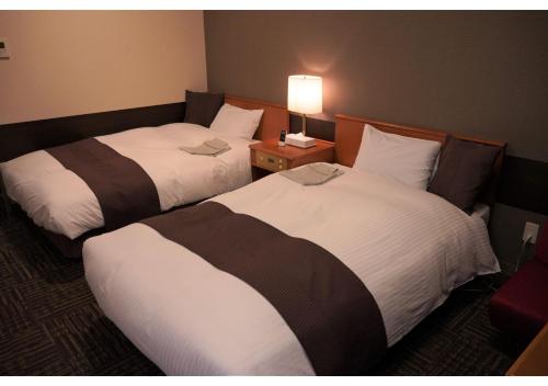 a hotel room with two beds and a lamp at Hotel Hachiman in Hachiman