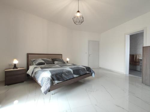 a white bedroom with a bed and a pendant light at Il-Girna in Marsaskala