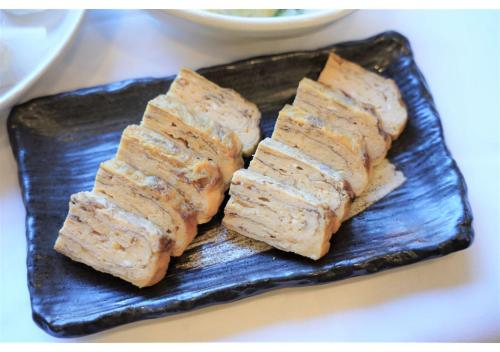 a black plate with three pieces of food on it at Hotel Hachiman in Hachiman