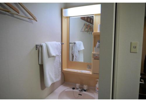 a bathroom with a mirror and a sink with towels at Hotel Hachiman in Hachiman