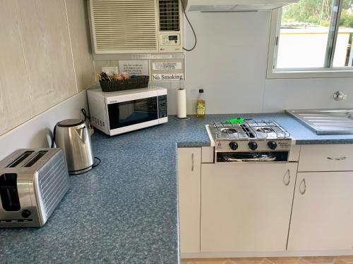 a kitchen with a microwave and a stove top oven at Cootamundra Caravan Park in Cootamundra