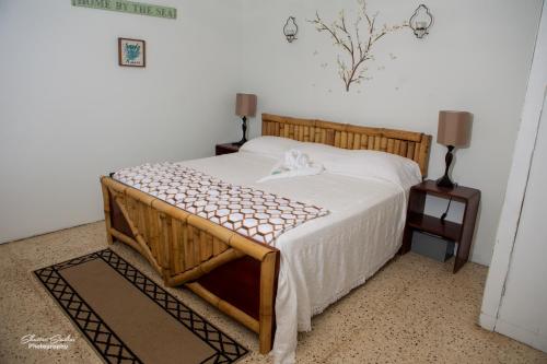 1 dormitorio con cama de madera con sábanas blancas en Treasure Beach Inn and Bar, en Treasure Beach