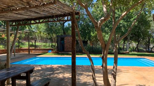 a swimming pool with a picnic table and a tree at Stay Harties Accommodation in Hartbeespoort