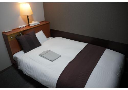 a bed in a hotel room with a book on it at Hotel Hachiman in Hachiman