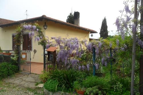 una cerca frente a una casa con flores púrpuras en Affittacamere DaMammaSara, en Rignano sullʼArno