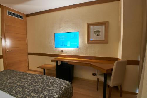 a bedroom with a bed, desk and television at Los Arcos in Segovia