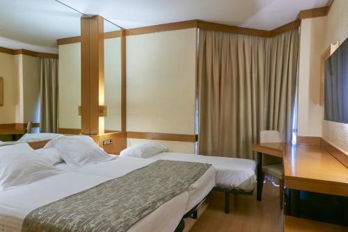 a hotel room with two beds and a desk at Los Arcos in Segovia