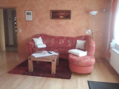 a living room with a red couch and a coffee table at Schöne Aussicht in Vöhl