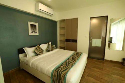 een slaapkamer met een groot bed met een groene muur bij 7 star Weekend studio at Rajhans Belliza by Global Hospitality in Surat