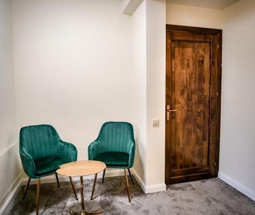 two green chairs and a table in a room at The Nest Boutique in Baia Mare