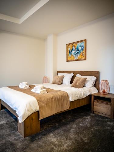 a bedroom with a large bed and a painting on the wall at The Nest Boutique in Baia Mare