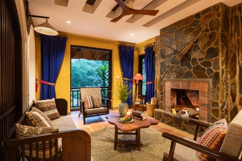 a living room with a large stone fireplace at Panhou Retreat in Ha Giang