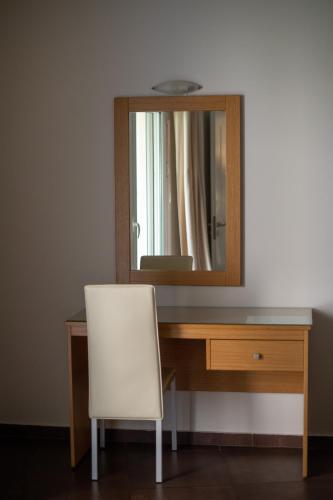 a white chair sitting in front of a desk with a mirror at Alkistis Hotel in Diakopto
